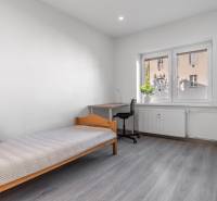 A room in a 3-room apartment with a bed, a table, and a floor with a wooden decor.