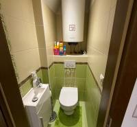 Bathroom in a 2-room apartment with a toilet and a sink, tiled with light tiles.