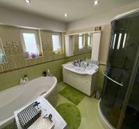 A bathroom in a 2-room apartment with a bathtub, shower, and green tiles.