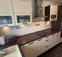 A kitchen in a 2-room apartment with white cabinets and a wood-patterned floor.