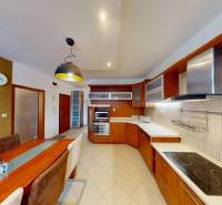 A kitchen in a 3-room apartment with built-in appliances and a spacious dining table.