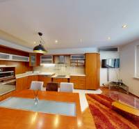 The kitchen of a three-room apartment with a wooden decor floor and a dining table.