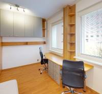 A workspace in a 3-room apartment with storage cabinets and a view from a large window.