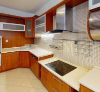 A kitchen in a 3-room apartment with a wooden decor kitchen unit and glass cabinets.