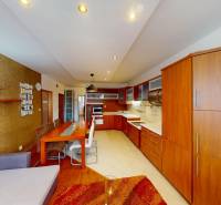 Living room and kitchen in a 3-room apartment with a wooden decor floor and a comfortable sofa set.