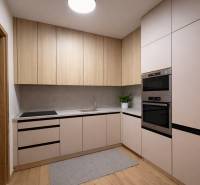 A kitchen in a studio apartment with a wood-patterned floor and modern appliances.