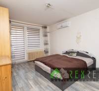 Bedroom in a 3-room apartment with wood-patterned flooring, a bed, and a cabinet.