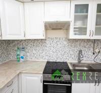 A kitchen in a 3-room apartment with white cabinets and mosaic tiles.