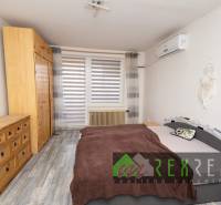 Bedroom in a 3-room apartment with wood-patterned flooring, a wardrobe, and a bed.