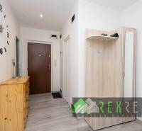 A hallway of a 3-room apartment with a coat rack, furniture, and flooring with a wooden decor.