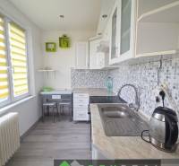 A kitchen in a 3-room apartment with a wood-patterned floor and light cabinets.