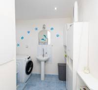 A bathroom with light cabinets, a sink, and a washing machine in a 3-room apartment.