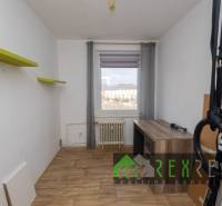 A room with a wooden decor floor in a 3-room apartment, with a view of the city.