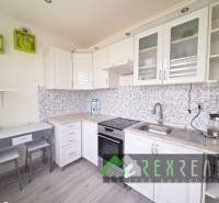A kitchen in a 3-room apartment with mosaic tiles and a floor with a wooden decor.