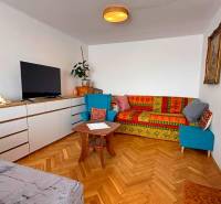 A living room in a 3-room apartment with a wooden decor floor and colorful sofas.