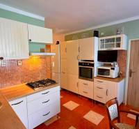 A kitchen in a 3-room apartment with a stove, sink, and cabinets for storage.