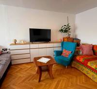Living room in a three-room apartment with a wooden decor floor, sofas, and a television.