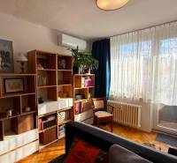 Living room in a 3-room apartment with a wooden decor floor, a bookshelf, and comfortable seating.