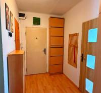 A hallway in a 3-room apartment with light furniture and a wooden decor floor.