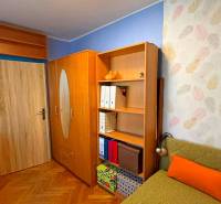 A room in a 3-room apartment with a wood-patterned floor and colorful wallpaper.