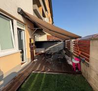 Terrace of a 2-room apartment in Most pri Bratislave with a view of the garden and seating area.
