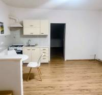 A kitchen in a family house with a wooden decor floor and simple furniture.