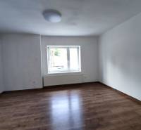 A room in a family house with neutrally painted walls and a wooden decor floor.