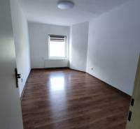 A spacious room in a family house with a wooden decor floor and white walls.