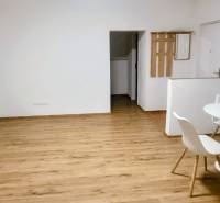 A room with a wooden decor floor, a white table, and chairs in a family house.
