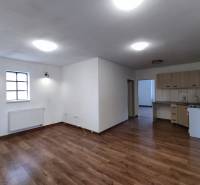 Interior of a family house with a kitchen, wood-patterned flooring, and white walls.