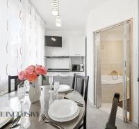 A dining room with flowers and a kitchen in a 3-room apartment, next to a bathroom with a corner bathtub.