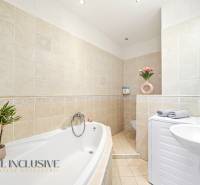 Bathroom in a 3-room apartment with a bathtub, sink, washing machine, and a decorative plant.