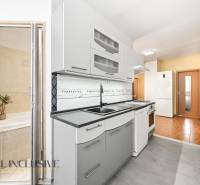 A kitchen in a 3-room apartment with white cabinets and a tiled wall.