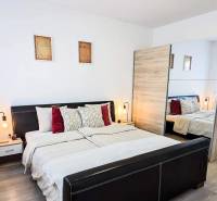 Bedroom in a 2-room apartment with a wood-patterned floor and a large mirror.