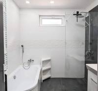Bathroom in a 2-room apartment with a bathtub and shower, white tiles.