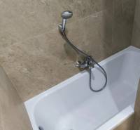 A bathroom in a 4-room apartment with a bathtub lined with light ceramic tiles.
