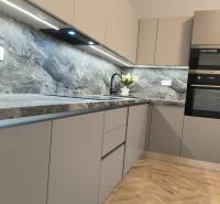 A kitchen in a 4-room apartment with a wood-patterned floor and a stone countertop.