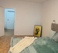 Bedroom in a 4-room apartment with a bed, wood-patterned flooring, and a modern chandelier.