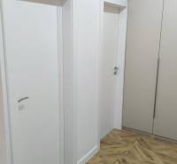Interior of a 4-room apartment with white doors, cabinets, and a floor with a wood decor.