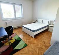 Bright bedroom in a three-room apartment with wood-patterned flooring and a writing desk.