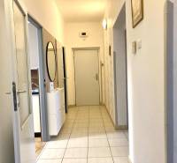 A hallway in a 3-room apartment with light tiles and a mirror on the wall.