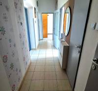 A hallway in a 3-room apartment with a tiled floor, a mirror, and patterned wallpaper.