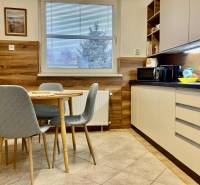 A kitchen in a 3-room apartment with a dining table, chairs, and a kitchen unit.