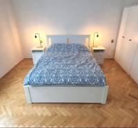 Bedroom with a bed, nightstands, and a wardrobe, floor with wood decor.