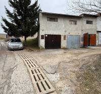 Garages on Prachatická Street in Zvolen with parked cars and trees.