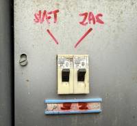 Circuit breakers with handwritten labels on a metal surface in the garage.