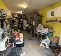 In the garage, various appliances, boxes, and a shelving system can be seen.