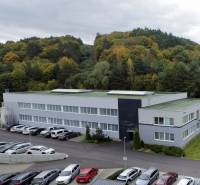 A building of warehouses and halls with a parking lot surrounded by trees on Trenčianska Road in Nová Dubnica.
