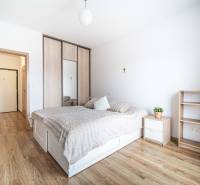 Bedroom with a bed, built-in wardrobe, dresser, and floor with wood decor in a 2-room apartment.