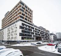 Snow-covered Zuzana Chalupová Street in Bratislava - Petržalka with a residential complex and cars.